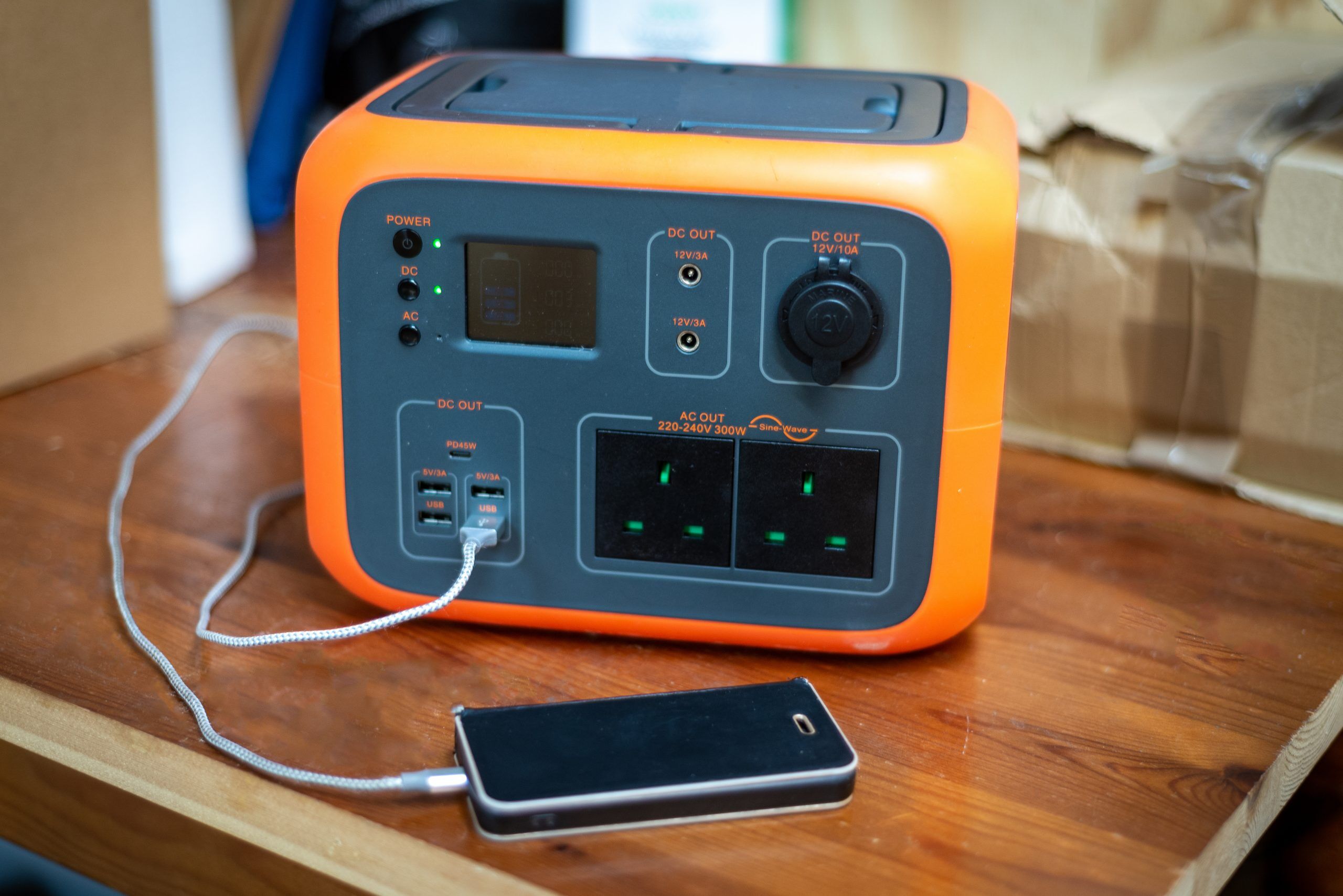 Portable power station solar electricity generator with mobile iPhone plugged in to charge.