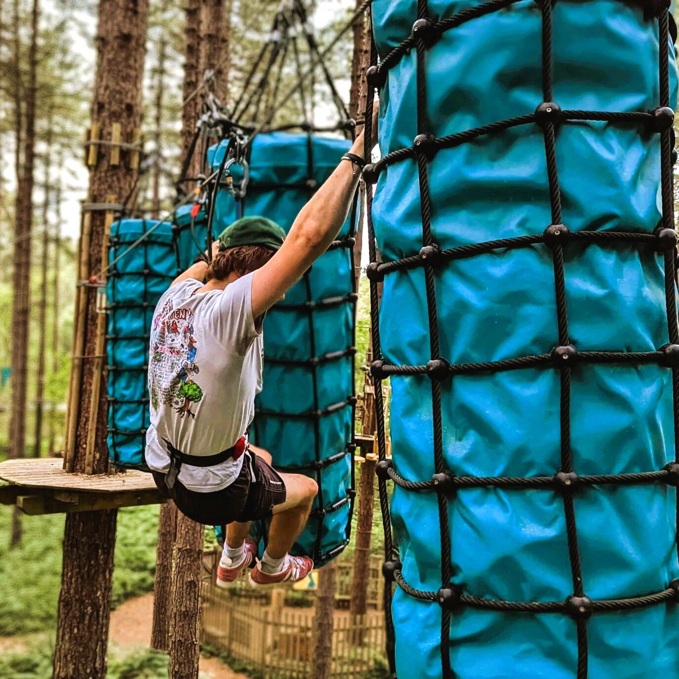 a man swinging between two obstacles at go ape treetop challenge plus