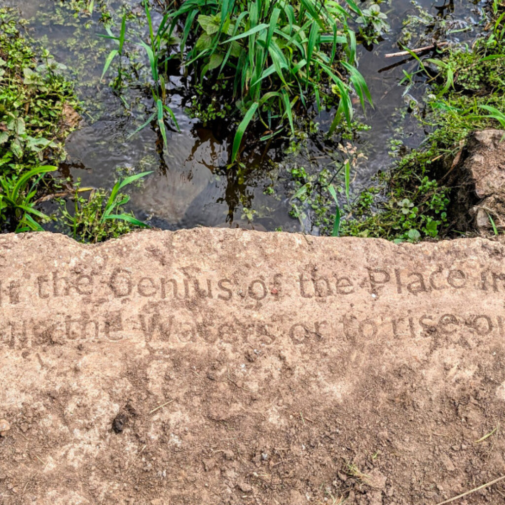 an image of a slab of rock with an enscription on it reading Consult the Genius of the Place in all; That tells the Waters or to rise or fall