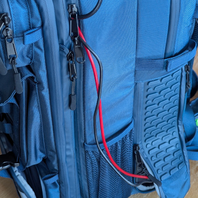 A close up shot of a blue backpack specifically made by Bluetti to hold a power station that can charge gadgets while on the move. There are cables visible from equipment to power supply