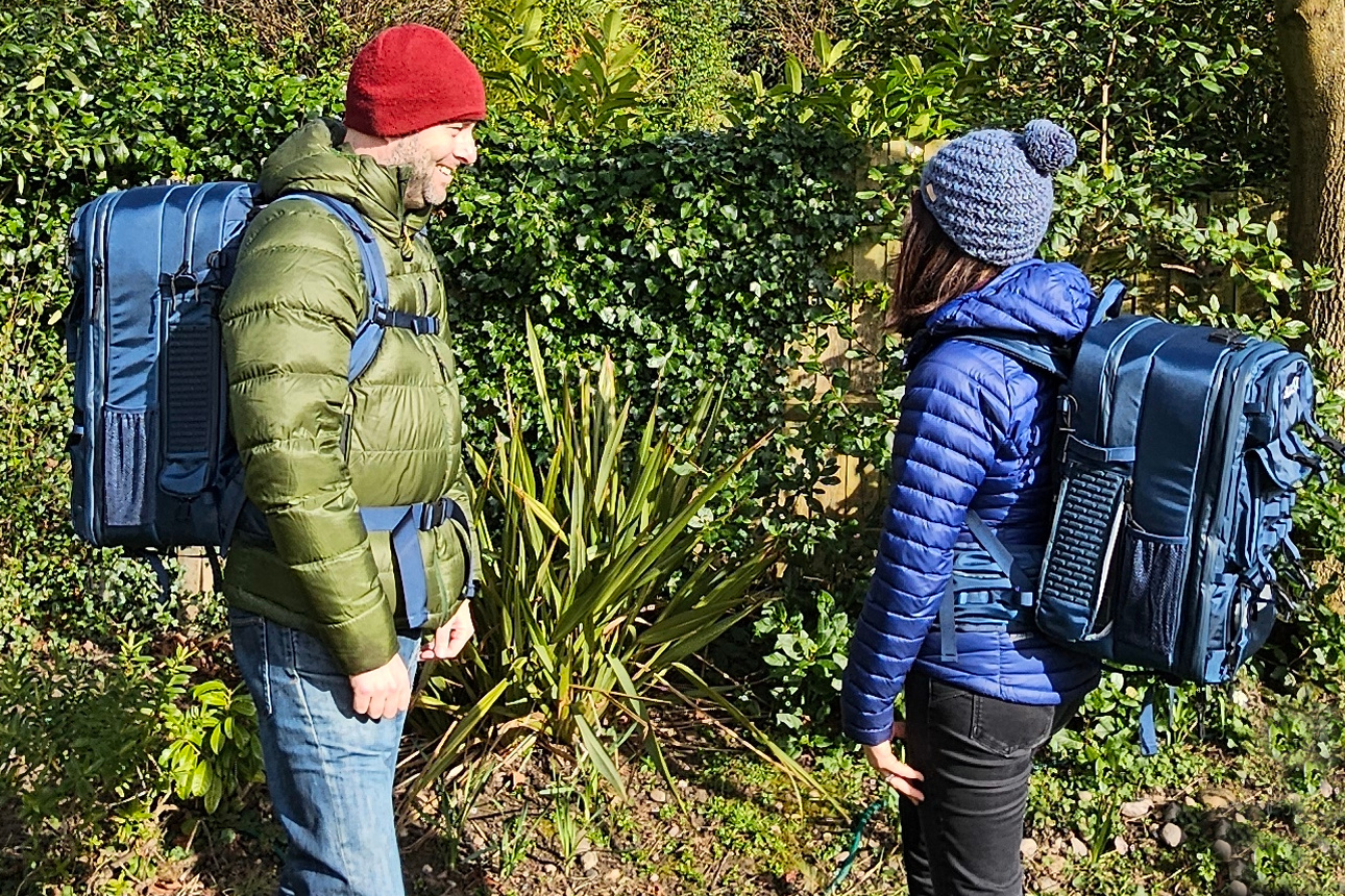 a side profile shot of the bluetti blue coloured backpack shown in different sizes and worn by a man and a woman.