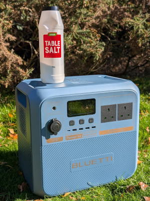 the Bluetti Pioneer Na power station sitting on the grass with a tub of table salt sitting on top